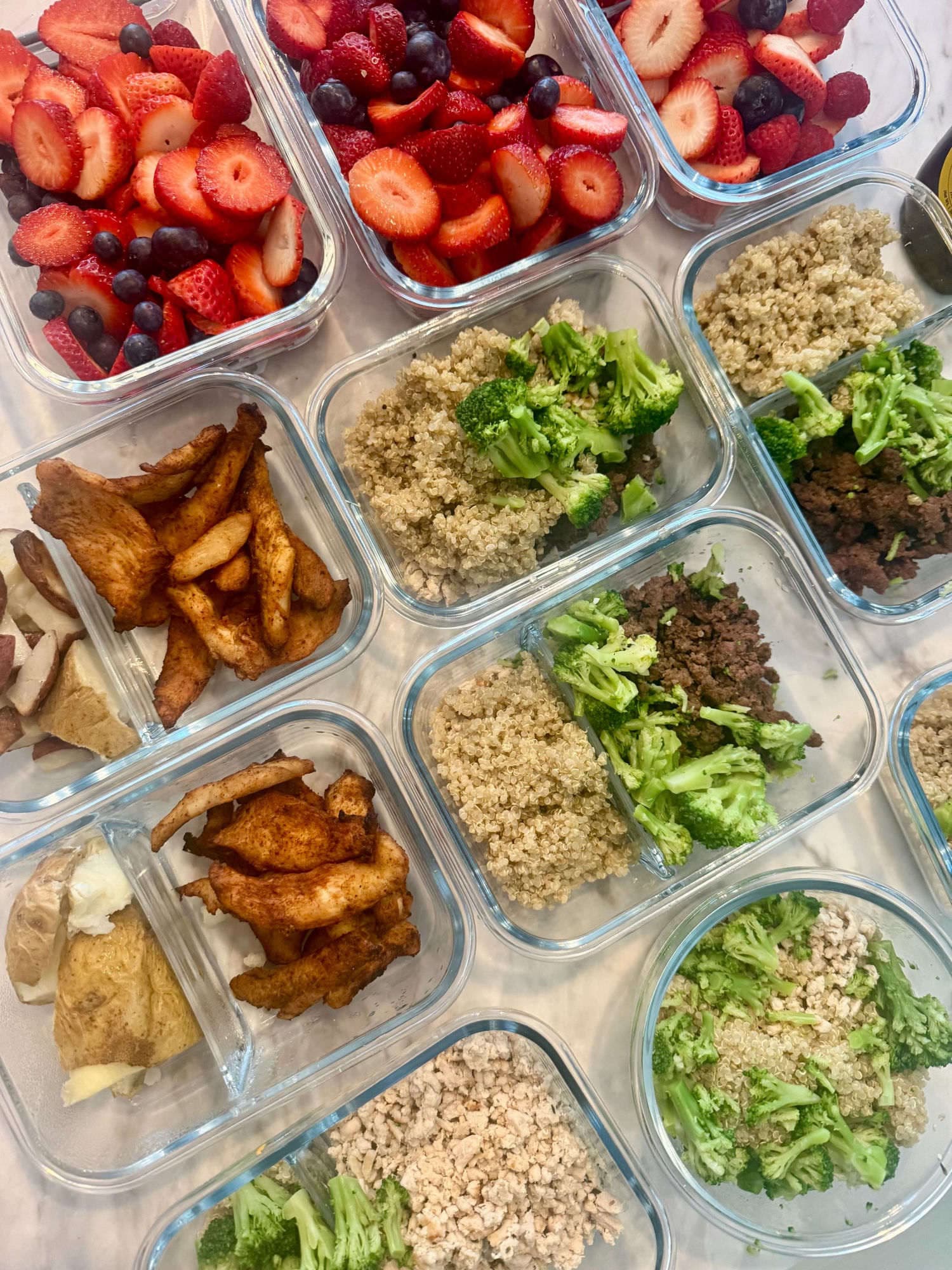 Glass meal-prep bowls of quinoa, broccoli, lean protein and fresh berries